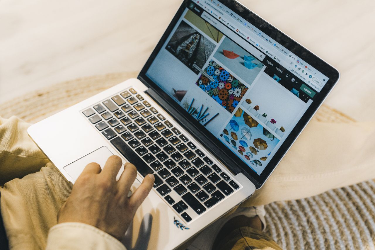 home-hero A person using a laptop to browse stock photo websites. Freelancing work in a cozy setting.
