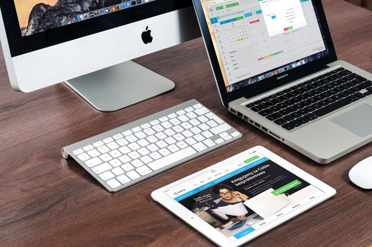 why-choose-us Un élégant aménagement de bureau mettant en avant des appareils Apple : iMac, MacBook et iPad.